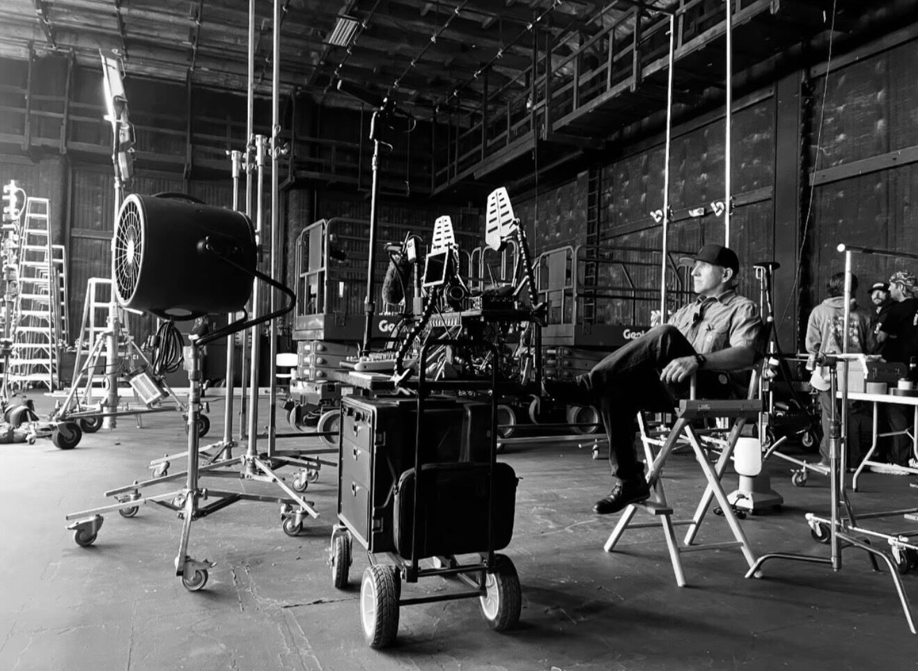 Luis Martinez in a director's chair on a soundstage, his rolling prop cart beside him